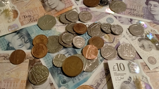 A scattering of variously-denominated UK banknotes and coins